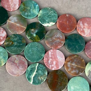 Può includere: Una collezione di cabochon in pietra circolari caratterizzati da una varietà di motivi e colori naturali, tra cui sfumature di verde bosco, verde muschio, terracotta, rosa antico e marrone terra, con texture marmorizzate e superfici levigate.