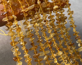 May include: Multiple strands of translucent, golden-yellow citrine gemstone chips are strung together. Each strand features irregularly shaped, polished stones with varying levels of clarity and depth, creating a cohesive, warm-toned collection of natural mineral beads.