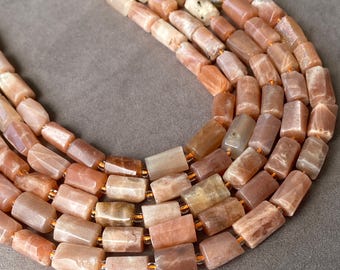 May include: A multi-strand necklace featuring cylindrical, polished peach and tan sunstone beads. The beads are strung on a thin, flexible cord, showcasing natural variations in color, translucency, and texture across the smooth, rectangular-shaped stone segments.