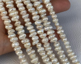 May include: A collection of five strands of white freshwater pearls, each featuring an irregular, organic shape with a high-luster finish. The pearls are strung together in vertical lines, showcasing their natural texture and iridescent surface.