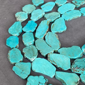 Könnte beinhalten: Eine Sammlung flacher, unregelmäßiger Türkissteine in leuchtenden Cyan- und Petroltönen mit dunkelbrauner Matrix-Maserung. Diese polierten, plattenartigen Stücke sind in einer lockeren Gruppe angeordnet und zeigen vielfältige organische Formen.