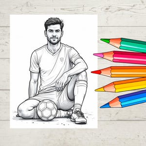 May include: Black and white coloring page of a soccer player sitting with a soccer ball. The player is wearing a white uniform. Six colored pencils in green, pink, red, orange, yellow, and blue are on a wooden surface.