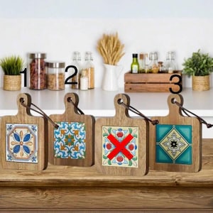 May include: Three wooden chopping boards with colourful tile designs. The boards have a handle and are perfect for serving or displaying. The designs include a blue and yellow floral pattern, a green and blue floral pattern, and a red and yellow cross pattern.
