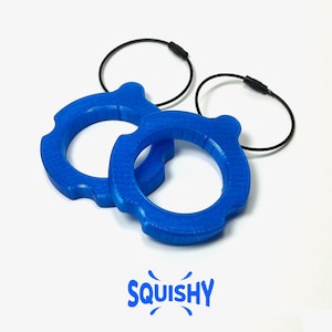 May include: Two bright blue, circular keychains with a unique gear-like design. Each keychain has a black loop attached. The word "SQUISHY" is printed in blue below the keychains.