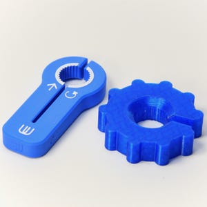 May include: Two blue plastic tools for opening cans. One tool is shaped like a key with a serrated edge and arrows indicating direction. The other tool is a ring with a serrated edge.