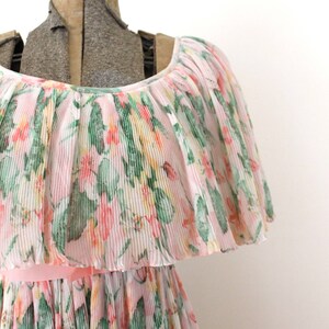 May include: A pink and white floral dress with a ruffled neckline and a pleated skirt. The dress is made of a lightweight fabric and has a delicate floral print.
