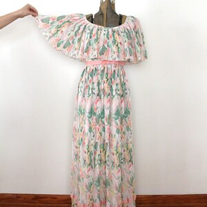 May include: A long, pink and white floral print dress with a ruffled off-the-shoulder neckline and a pink ribbon belt. The dress has a tiered skirt with pink ruffles at the hem.