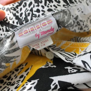 May include: A white and yellow patterned shirt with a black and white print. The shirt has a label that reads "anlya by Mandy" and "Style S7103 Size 7/8".