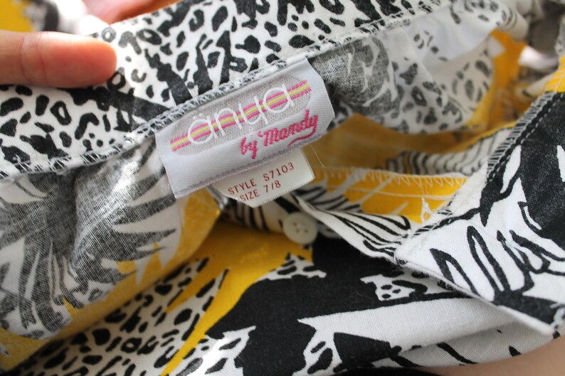 May include: A white and yellow patterned shirt with a black and white print. The shirt has a label that reads "anlya by Mandy" and "Style S7103 Size 7/8".