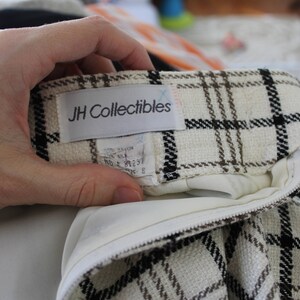 May include: A white and brown plaid skirt with a black zipper and a white label that says "JH Collectibles".
