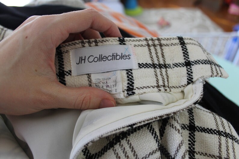 May include: A white and brown plaid skirt with a black zipper and a white label that says "JH Collectibles".