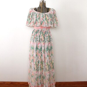 May include: A long, pink and white floral print dress with a ruffled neckline and a pink sash. The dress has a tiered skirt and is made of a lightweight fabric.
