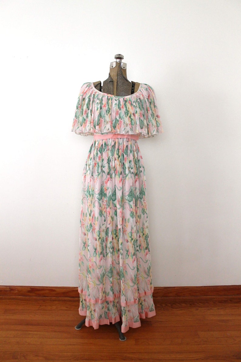 May include: A long, pink and white floral print dress with a ruffled neckline and a pink sash. The dress has a tiered skirt and is made of a lightweight fabric.