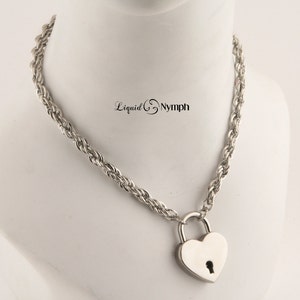May include: A silver rope chain necklace with a heart-shaped padlock pendant. The chain is twisted and the padlock has a keyhole.