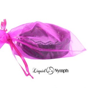 May include: A pink organza bag with a black lace trim, tied with a pink ribbon. The bag is filled with a black lace choker.