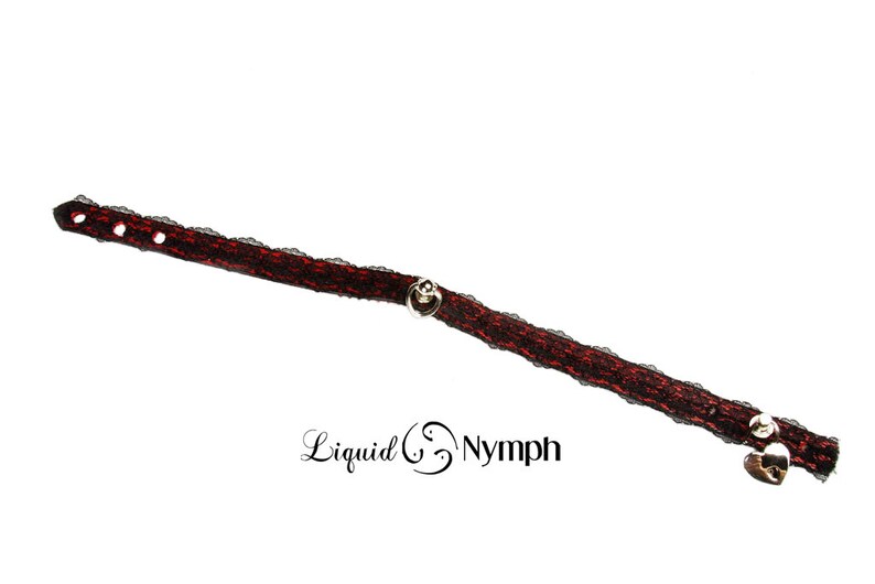 May include: A black and red lace choker with silver heart-shaped charms and a silver bell charm.