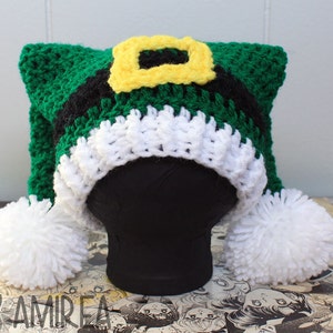 May include: Green and white crocheted elf hat with a black and yellow buckle. The hat has two white pom-poms.