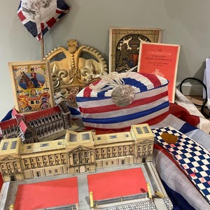 May include: A collection of vintage coronation memorabilia, including a paper model of Buckingham Palace, a crown, a flag, and a booklet titled "The Coronation of Her Majesty Queen Elizabeth II".