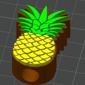 May include: 3D-printed pineapple-shaped object. The pineapple features a yellow body with a textured pattern and green leaves. The base is brown, and the design is rendered against a gray grid background.