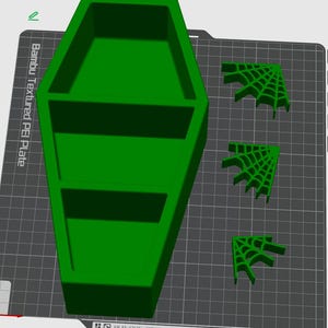 Puede incluir: Un recipiente verde brillante en forma de ataúd con dos estantes interiores y tres esquinas de telaraña verdes. Los artículos están impresos en 3D. El texto "Bambu Textured PEI Plate" es visible.