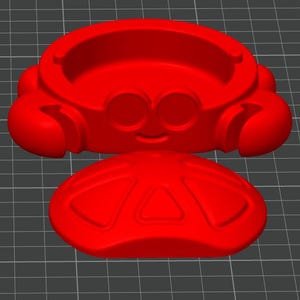 May include: A bright red, 3D-printed crab-shaped container with a lid. The container has a smiling face and rounded features. The lid has a triangular design. The object is on a gray grid.
