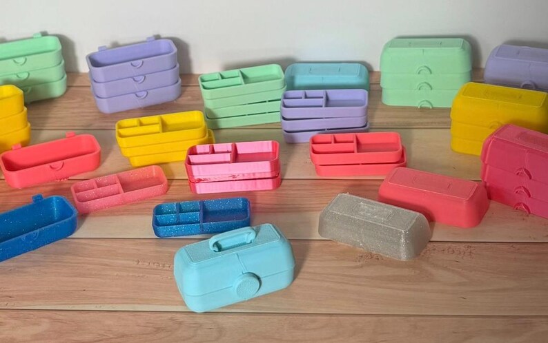 May include: A collection of colorful plastic organizers in various shapes and sizes. The organizers are in shades of pink, blue, yellow, green, and purple. Some have compartments, and others are stacked.