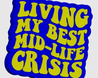 以下が含まれることがあります： レトロなフォントで「LIVING MY BEST MID-LIFE CRISIS」という言葉が入った青と黄色のグラフィック。テキストは黄色の青いアウトラインで、波状の縁を持つ青い背景に設定されています。