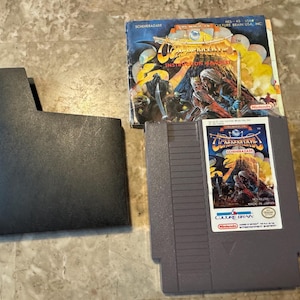 May include: A black Nintendo Entertainment System (NES) game cartridge with a gray label. The label features a colorful illustration of a fantasy scene with a dragon and knights. The text on the label reads "The Legend of Zelda: Shadow of the Sorcerer". The cartridge is accompanied by a black game case and a folded instruction manual with a similar illustration.