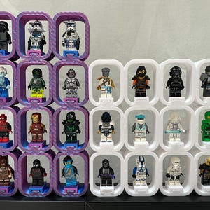 Könnte beinhalten: Eine Sammlung von Lego-Minifiguren, die in lila und weißen Aufbewahrungsboxen ausgestellt sind. Die Minifiguren stellen verschiedene Charaktere dar, darunter Superhelden und Science-Fiction-Figuren. Die Behälter sind in einem Raster angeordnet.