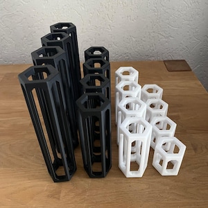 Può includere: Un set di organizzatori geometrici esagonali di colore nero e bianco. Gli organizzatori sono realizzati in plastica e sono disposti a forma di piramide.