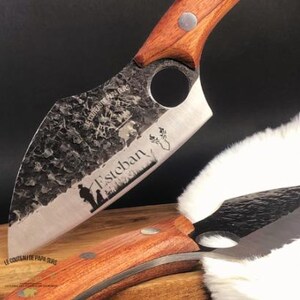 Peut inclure: Un couteau de chasse artisanal avec un manche en bois et une lame en acier inoxydable. La lame a une finition martelée et est gravée du texte "Esteban" et d'une scène de chasse.