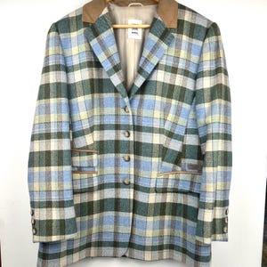 May include: A blazer featuring a plaid pattern in shades of light blue, dark green, and cream. The garment has a tan collar, four front buttons, two flap pockets, and three buttons on each cuff. A label inside reads "Musha".