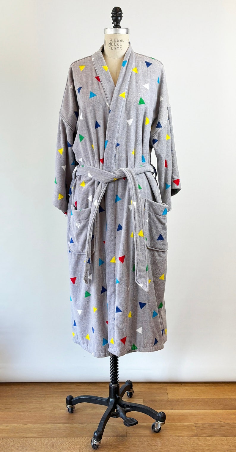 May include: Gray bathrobe with a colorful geometric pattern of triangles. The robe has a tie belt and two pockets.