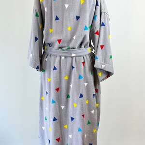 May include: Gray robe with a colorful triangle pattern. The robe has a tie belt and long sleeves.