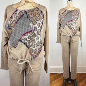 May include: A tan lounge set comprising a long-sleeved top and trousers. The top features a distinctive patchwork design with leopard print and patterned fabric. The trousers have a drawstring waist. The set is displayed on a mannequin.