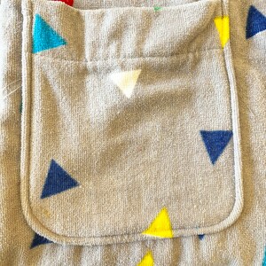 May include: A gray hooded towel with a pocket on the front. The towel has a pattern of colorful triangles.