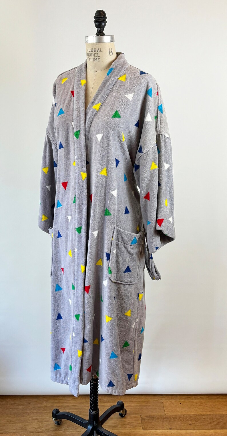 May include: Gray robe with a colorful triangle pattern. The robe has a tie belt and two pockets.