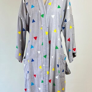 May include: A gray robe with a colorful triangle pattern. The robe has a long sleeve and a tie closure.