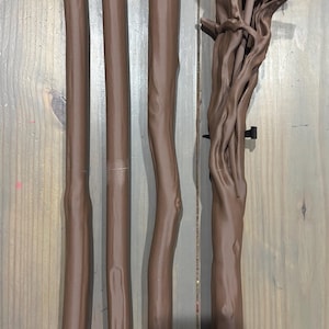 May include: A collection of brown, tree-like components, likely for a decorative or functional item. The pieces vary in shape and size, with some appearing to be straight poles and others more organically shaped. The color is a consistent, warm brown.