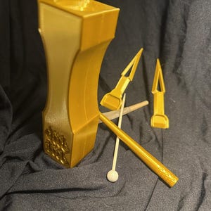 May include: A gold-colored wooden mallet with a decorative design and two gold-colored wooden strikers.
