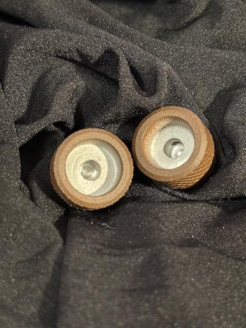 May include: Two wooden tops with a white center and a brown outer ring. The tops have a small hole in the center.