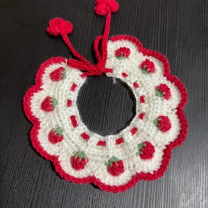 May include: White crocheted collar with red trim and strawberry designs.