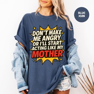 May include: A navy blue t-shirt with the slogan "DON'T MAKE ME ANGRY OR I'LL START ACTING LIKE MY MOTHER" in a yellow and red comic book style design. The shirt has rolled-up sleeves and is paired with a denim jacket.