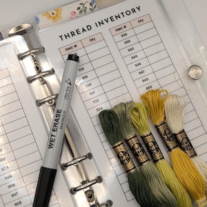 May include: A clear binder with a "THREAD INVENTORY" sheet, a black marker, and several skeins of embroidery floss in shades of green, yellow, and cream. The marker reads "WET ERASE MARKER".