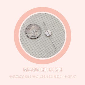 Peut inclure: Un aimant argent&eacute; et une aiguille &agrave; c&ocirc;t&eacute; d'une pi&egrave;ce de monnaie de 25 cents, sur un fond de tissu gris clair. Le texte "MAGNET SIZE" et "QUARTER FOR REFERENCE ONLY" est affich&eacute; en dessous, dans un cercle rose.