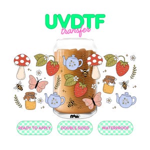 May include: A clear glass can-shaped UVDTF transfer with a whimsical design. The design includes strawberries, mushrooms, bees, butterflies, teapots, and honey jars. The text "READY TO APPLY", "DOUBLE SIDED", and "WATERPROOF" are also included.