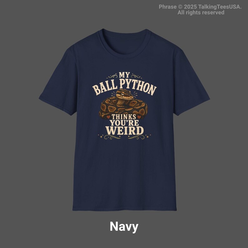 May include: A navy blue short-sleeve t-shirt featuring a graphic of a coiled ball python snake. The text printed in cream-colored lettering reads: MY BALL PYTHON THINKS YOU'RE WEIRD. The design includes decorative flourishes and small heart accents.