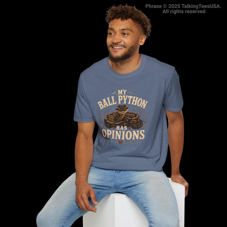 Pu&ograve; includere: Una t-shirt a maniche corte blu m&eacute;lange con la grafica di un pitone reale avvolto. Il testo "MY BALL PYTHON HAS OPINIONS" &egrave; stampato in beige, con una piccola icona a forma di cuore rosso sotto l'illustrazione del serpente sul petto.