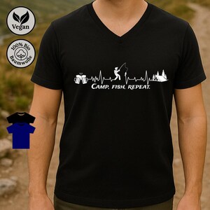 Könnte beinhalten: Schwarzes V-Ausschnitt-T-Shirt mit weißem Grafikdesign. Das Design umfasst Bierkrüge, einen Fischer, ein Zelt und den Text "CAMP, FISH, REPEAT". Das Shirt zeigt auch vegane und Baumwollsymbole.