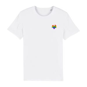 Könnte beinhalten: Ein weißes Kurzarm-T-Shirt mit einer kleinen Grafik im oberen linken Brustbereich. Die Grafik zeigt ein Herz, das mit einem lebendigen, mehrfarbigen Regenbogen-Aquarell-Farbspritzer-Design gefüllt ist, inklusive einzelner kleiner Farbtropfen.